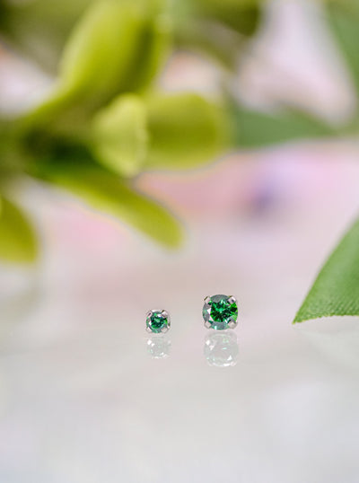 two emerald green earrings on titanium setting
